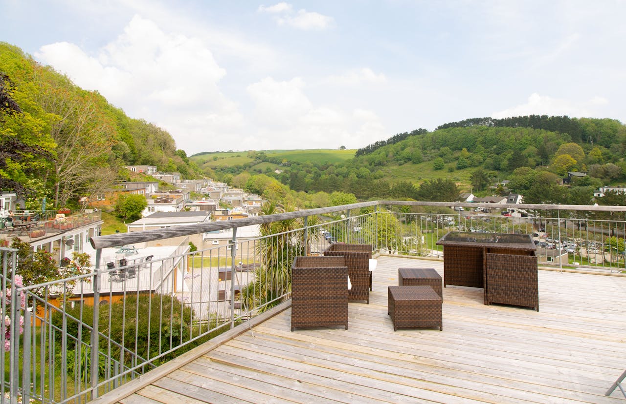 Spacious terrace with rattan furniture overlooking a scenic rural landscape.