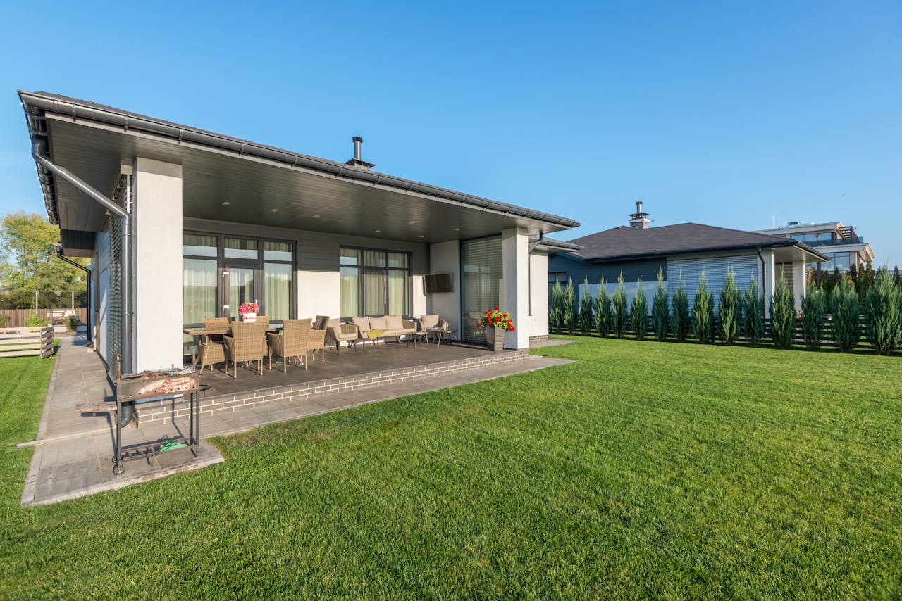 A modern house with a wide patio and neatly landscaped backyard, ideal for real estate and architecture themes.